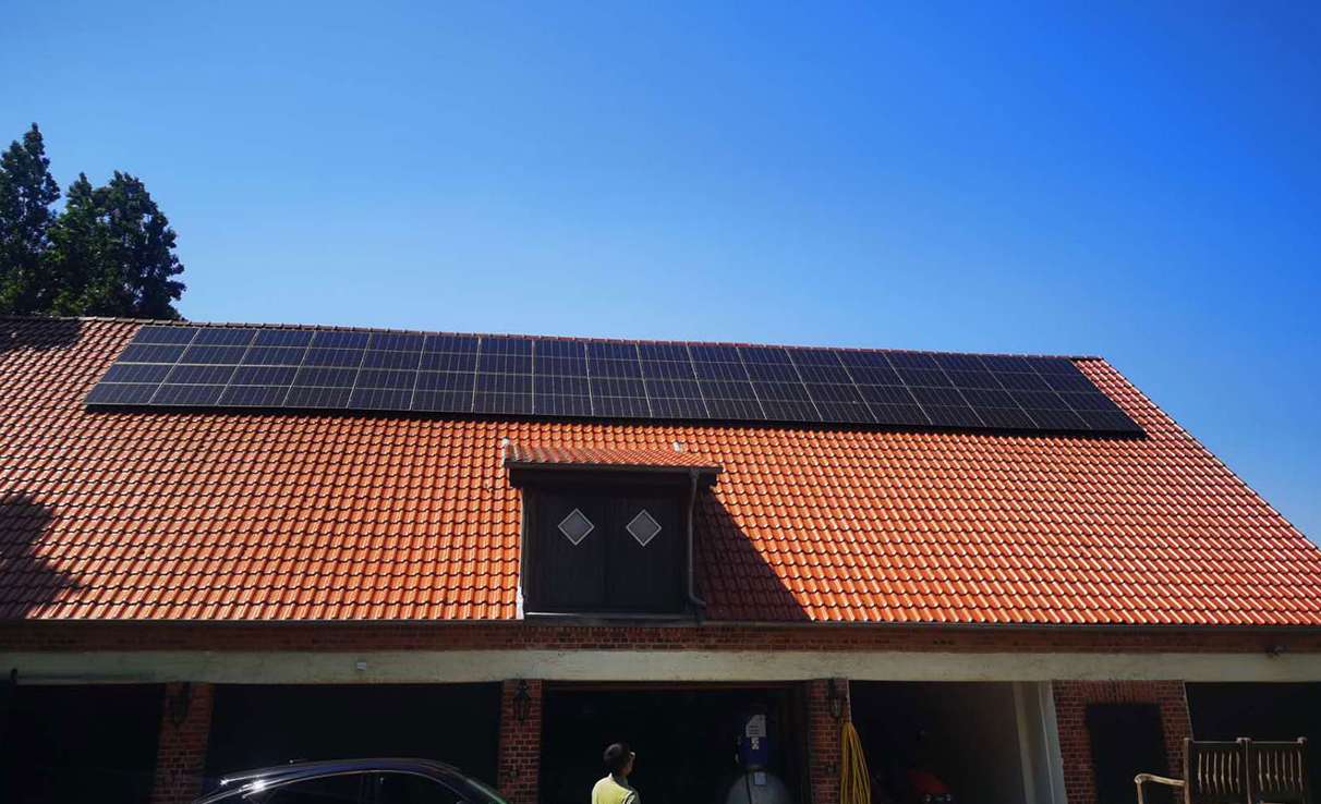 A residential pitched red-tile roof equipped with 24 Solavita solar panels in a neat horizontal row, showcasing compatibility with traditional European architecture
