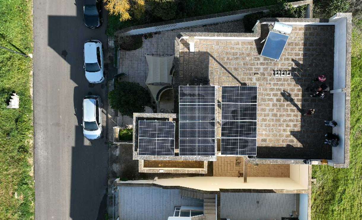 Top-down aerial view of a residential rooftop solar installation with 15 Solavita PV panels arranged in three compact arrays, alongside a solar thermal water heater