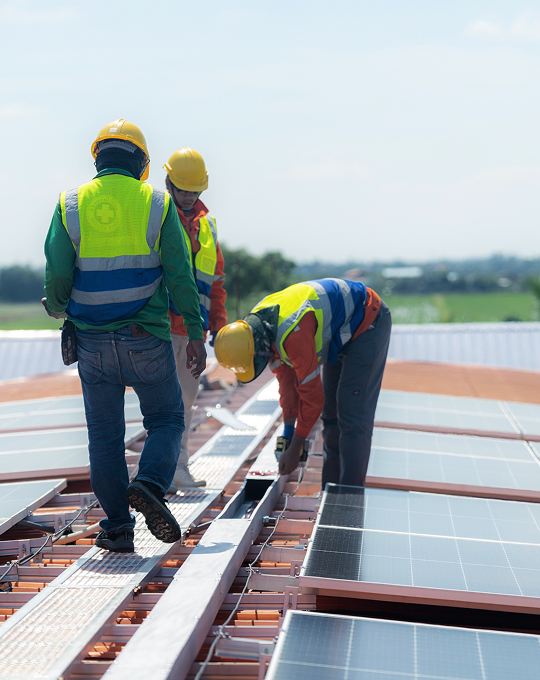 Technicians installing rooftop solar PV panels at an industrial site, demonstrating safe and professional construction by Solavita.